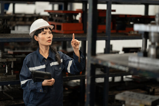 Industrial inspector woman examining metal parts in warehouse