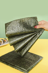 Hand Holding Nori Seaweed Sheets for Sushi Preparation © LyVan