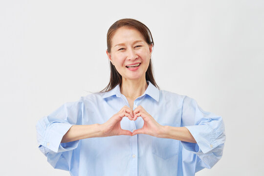 白背景でハートポーズをする女性