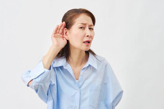 白背景で耳に手を当てる高齢女性