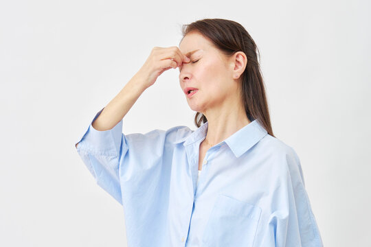 白背景で目頭を押さえる女性