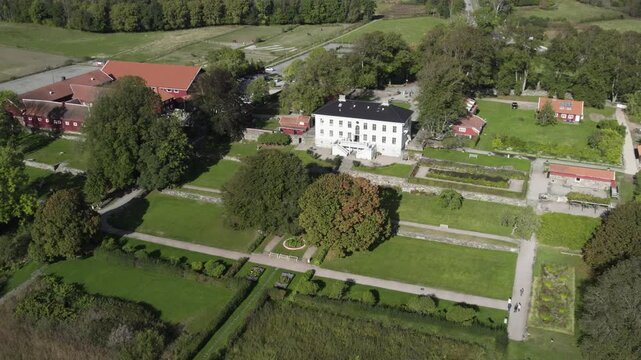 R&aring;da S&auml;teri historic manor estate in H&auml;rryda, Sweden. Aerial view of the elegant main building, symmetrical gardens, lush green landscape, and traditional outbuildings in a serene Scandinavian setting