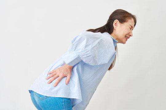 白背景で腰痛に悩む女性