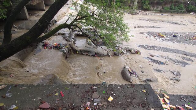 Polluted monsoon river flooding through urban canal pollution flood trash waste garbage