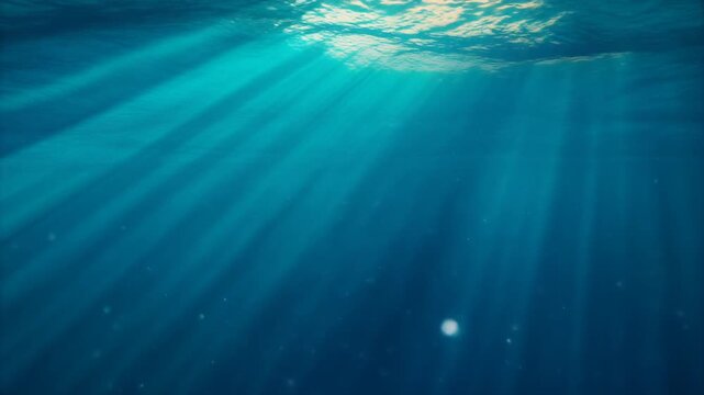 Sunbeams stream through the surface of clear turquoise ocean water into the deep blue sea.