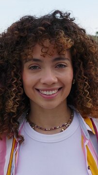Vertical HD video portrait of smiling young Latin American woman outdoors. Confident millennial female looking at the camera in the city. Lifestyle and wellbeing concept. 