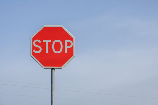 Red stop sign standing under clear blue sky