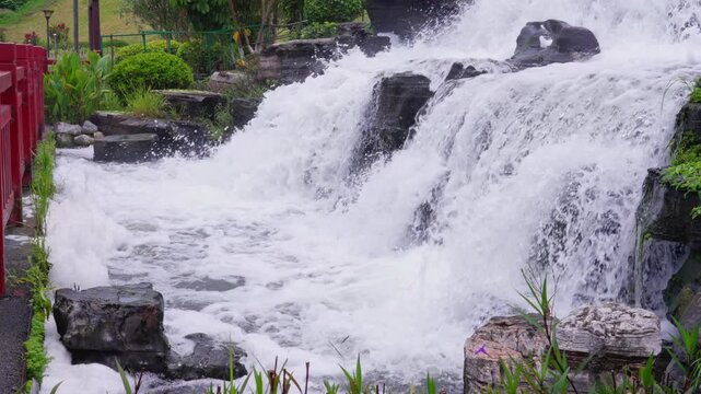 Garden multi-layered waterfall landscape next to red railing
