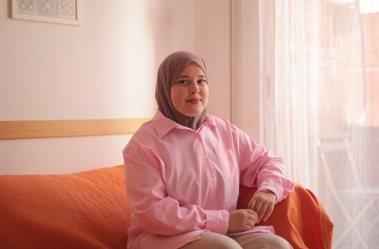 Young woman in hijab relaxing on a couch at home