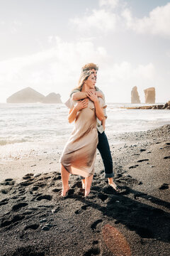 Young couple embracing on a volcanic sand beach