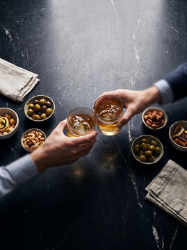 Top View People Toasting Whiskey Glasses with Nuts and Olives