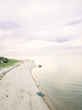 Quiet sandy beach curves along calm water with drone