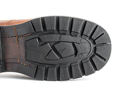 Close-up of a brown leather boot sole with a heavy-duty rubber traction tread