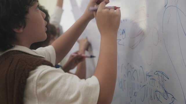 The children are drawing on the whiteboard in the classroom.