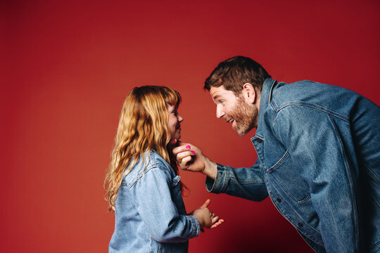 Father bending down to connect warmly with daughter in vibrant studio portrait