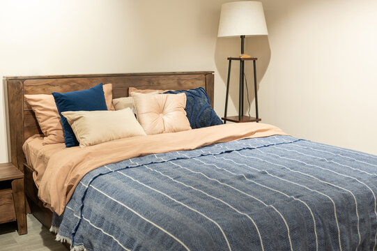 Cozy bedroom with wooden headboard, blue and beige bedding, and floor lamp