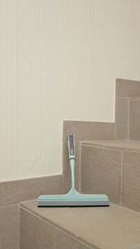 Aqua squeegee on tiled staircase corner for efficient home cleaning