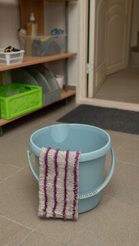 Empty blue bucket with striped cloth in tiled laundry room