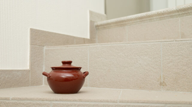 Brown ceramic pot on beige tiled staircase corner