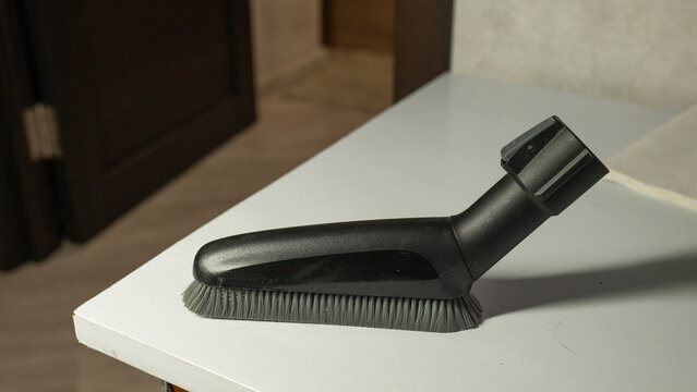Black vacuum cleaner brush attachment on white table