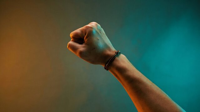 Raised human fist symbolizing strength determination and empowerment on colorful background