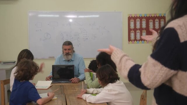 The teacher is teaching the children in the classroom.