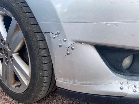 Nahaufnahme einer besch&auml;digten Sto&szlig;stange mit Lackschaden und Riss nach einem Parkrempler. Thema Autounfall, Kfz-Schaden, Reparatur, Versicherung und Wertminderung.