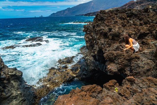 Woman exploring volcanic rocks and ocean waves on el hierro island