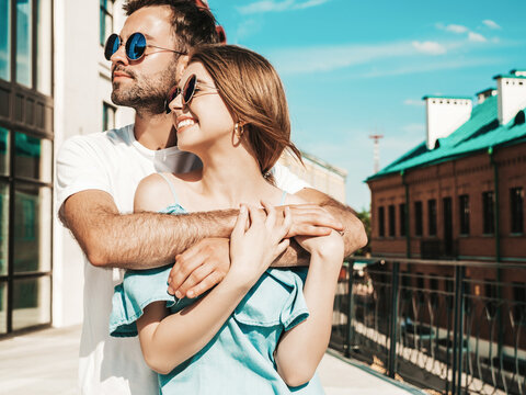 Portrait of smiling beautiful female and her handsome boyfriend. Woman in casual summer jeans dress. Happy cheerful family. Female having fun. Couple posing on the street background in sunglasses