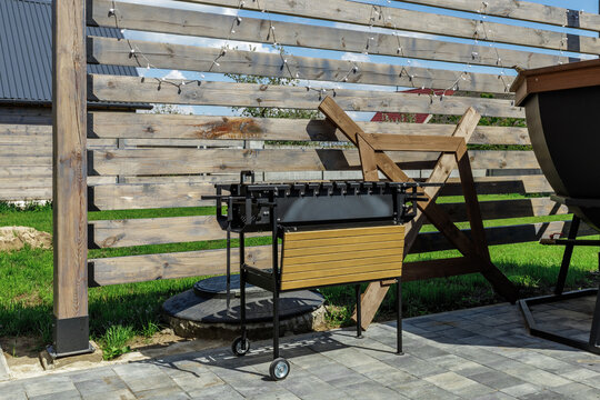 Mobile Metal Grill on Backyard Patio Against Wooden Fence