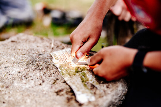 Close up of hands striking a ferro rod to ignite birch bark outdoors