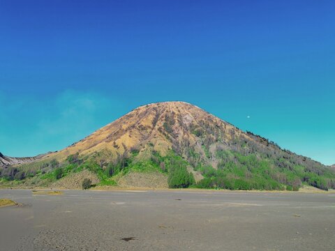Mount Batok rising above the volcanic sand sea in Bromo Tengger Semeru National Park, East Java, Indonesia, beneath a clear blue sky