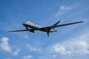 Fototapeta premium Militärische Kampfdrohne (UAV) im Flug am blauen Himmel. Unbemanntes Luftfahrzeug auf Aufklärungs- und Angriffsmission. Konzept für moderne Kriegsführung und Bedrohung aus der Luft