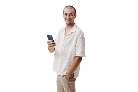 Smiling Young Man Holding Smartphone with Hand in Pocket on Beige Background