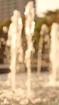 A Beautiful Display of Water Fountains Captured in Soft Focus, Showcasing the Dance of Water Streams Under Bright Sunlight in a Lively Urban Setting