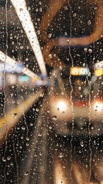 A mesmerizing view through water droplets on glass, showcasing vibrant colors and blurred lights, creating an artistic representation of a rainy urban scene at a train station.