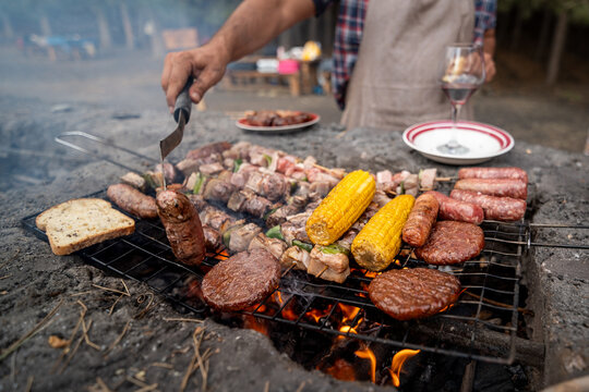 Hands flip sizzling meats over glowing coals. Hands flip sizzling meats over glowing coals