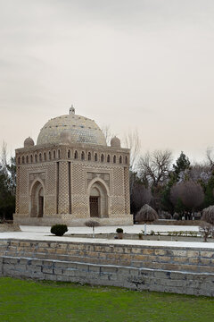 Ismail Samani Mausoleum in Bukhara featuring intricate brickwork patterns and a dome surrounded by a park. Historic Uzbekistan landmark ideal for travel and heritage publications.
