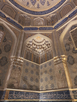 Ornate interior of a mausoleum at Shah-i-Zinda necropolis in Samarkand featuring muqarnas vault and intricate tilework. Ideal for travel publications, cultural heritage materials, architectural.