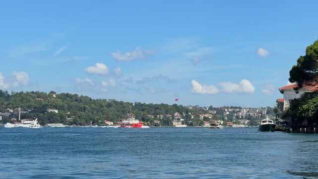 Traditional waterfront houses line the Bosphorus shoreline near Beykoz Istanbul as boats rest calmly along the coast under blue sky