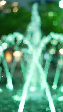 A Serene Water Fountain Illuminated in Green Light, Creating an Enchanting Atmosphere with Dynamic Water Sprays and Captivating Surroundings