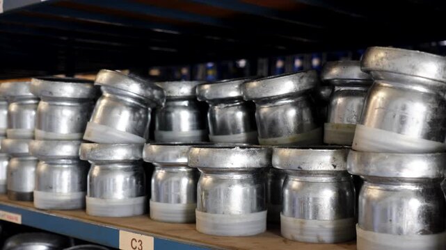 Metal pipe couplings stacked on warehouse shelf for industrial irrigation systems, medium closeup
