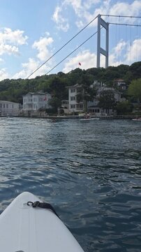 Boat trip view of Fatih Sultan Mehmet Bridge and Anadolu Hisari coastline on the Bosphorus in Beykoz Istanbul with calm water and green hills