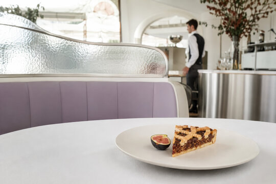 Una deliciosa crostata de higo se encuentra en la mesa en un restaurante moderno con un camarero al fondo