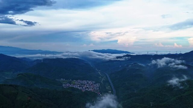 Time-Lapse of Sea of Clouds Over Forest Mountains with Wind Turbines and Winding Highway Traffic