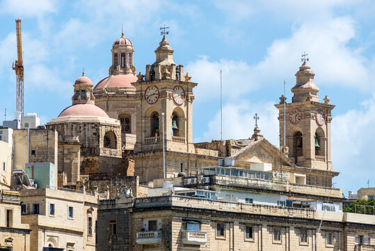 The Church of the Immaculate Conception in Cospicua rises with domes, clock towers and ornate stonework, showcasing Malta&rsquo;s rich architectural heritage against a bright Mediterranean sky