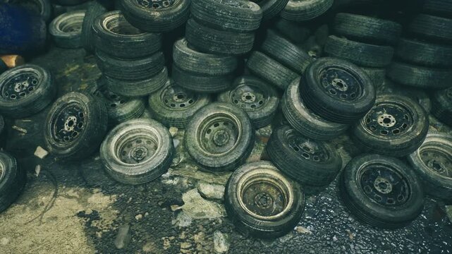 Dense stacks of tires in dim warehouse setting, layered rows showing texture of worn treads and rims, gritty floor with oil stains, atmosphere suited