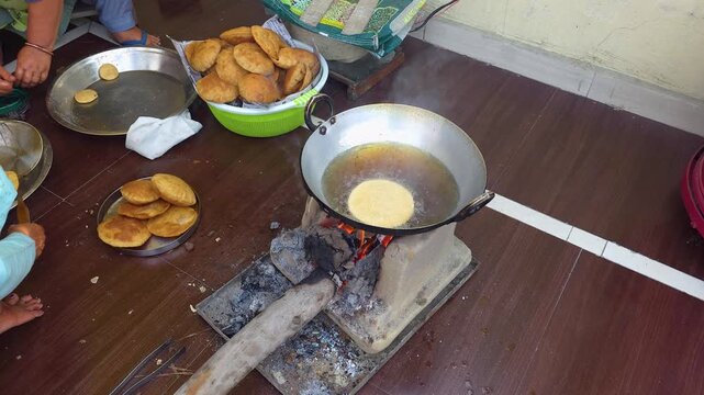 Traditional indian street food cooking poori fried in hot oil on rustic wood burning stove