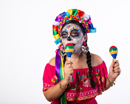 Joyful Woman with Day of the Dead Makeup Holding Colorful Maracas on White Background