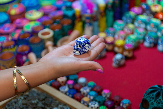 Hand Holding Miniature Blue Ceramic Skull at Traditional Mexican Artisan Market